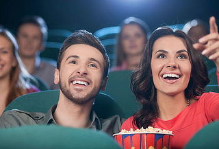 Foto de dos personas mirando una pantalla de cine con popcorn en sus manos